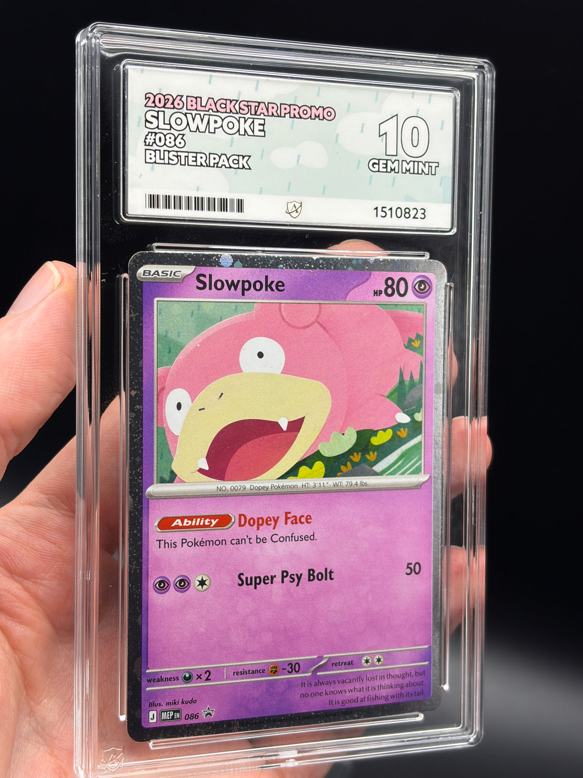 Handheld close-up of English Slowpoke #086 Black Star Promo 2026 Pokémon card in an ACE 10 Gem Mint slab, showing artwork and grading label